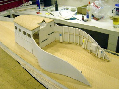 View of the spray shields from port side. First order of business was to form the base of the shield. This was fabricated from 1/8" aircraft plywood using a pattern I made directly from the plans to get the correct shape. The shields are an odd structure. Lots of compound curves. Once the bases were completed, I formed the actual shields from 1/32 veener. This piece was then sandwiched between a layer of .015 styrene on the outside, and .010 styrene on the inside. The shield was then attached to the base, angling in slightly to conform with the pilothouse. Next, the horizonal braces were made with 1/16" balsa and the capped with 1/8" x .010 styrene. I then added the cross bracing which is 1/8" balsa stick. Next, a cap was added on the top edge of the shield using 1/16" styrene rod. Lastly, I added the vents and other items using balsa wrapped with styrene. Small colored squares on vents are vac formed louvers I made.