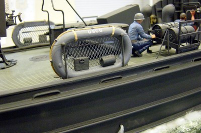 In this photo I have added details to the 5 man rafts. The water keg is styrene tube, ration/first aid box is balsa with a small cast metal handle, and the oar is cast metal. I have secured the raft to the safety cable with thin strips of automotive pin striping. Note the crewman on the D/C rack.