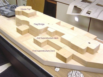 Here's a portside view looking fwd. Each level was traced out on the balsa, using plans from Floating Drydock, then cut out with a bandsaw and scrollsaw, then trued up with sandpaper. If you look at the outside edge of the first deck, you can see I have started to wrap the wood with styrene. Industrial grade contact adhesive used here. I'll continue to "wrap" each level in this way, adding the decks in between as I work my way up. I have noted the first few levels in the photo. Many more to go...... as I said, time consuming if it is to be correct!