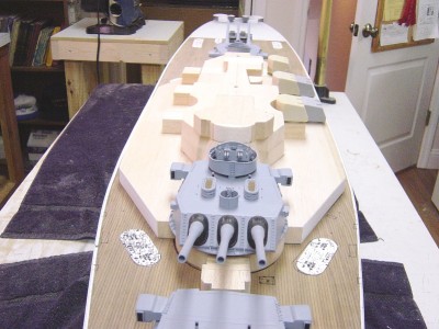 Dead on view here. Note #2 turrent in it's correct position. The superstructure is taking shape! Slowly..... The first deck also gets wood planking. The paper patterns you see will eventually become more parts.