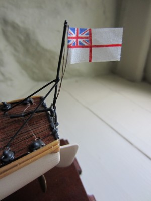 The fine silk ensign hanging from the stern .